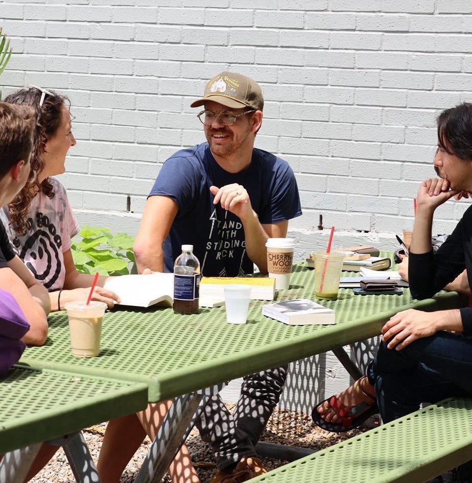 Bob Peck leading a book discussion at an outdoor patio table in Austin